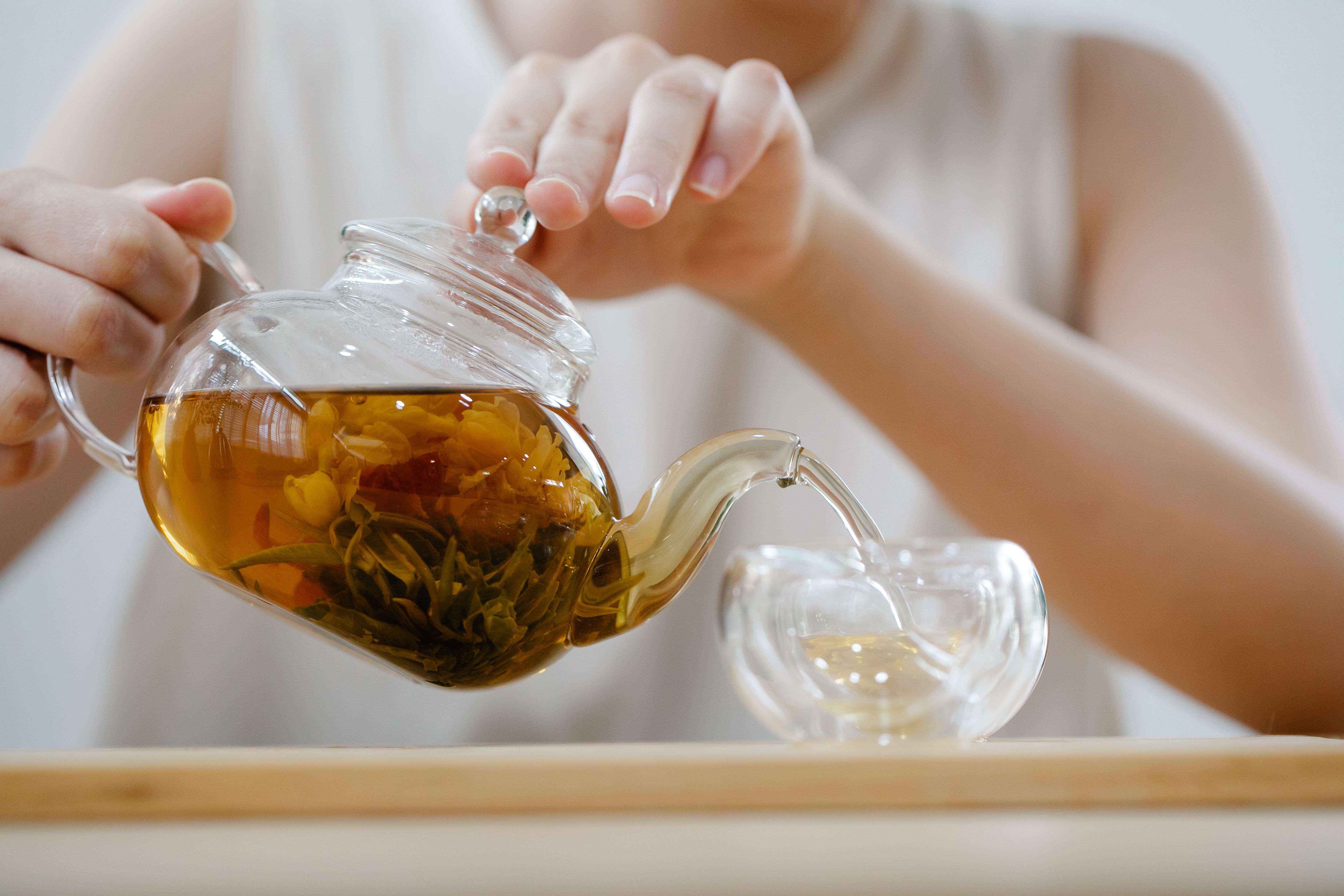 Woman pouring herbal tea into a cup during a cozy mindful ritual