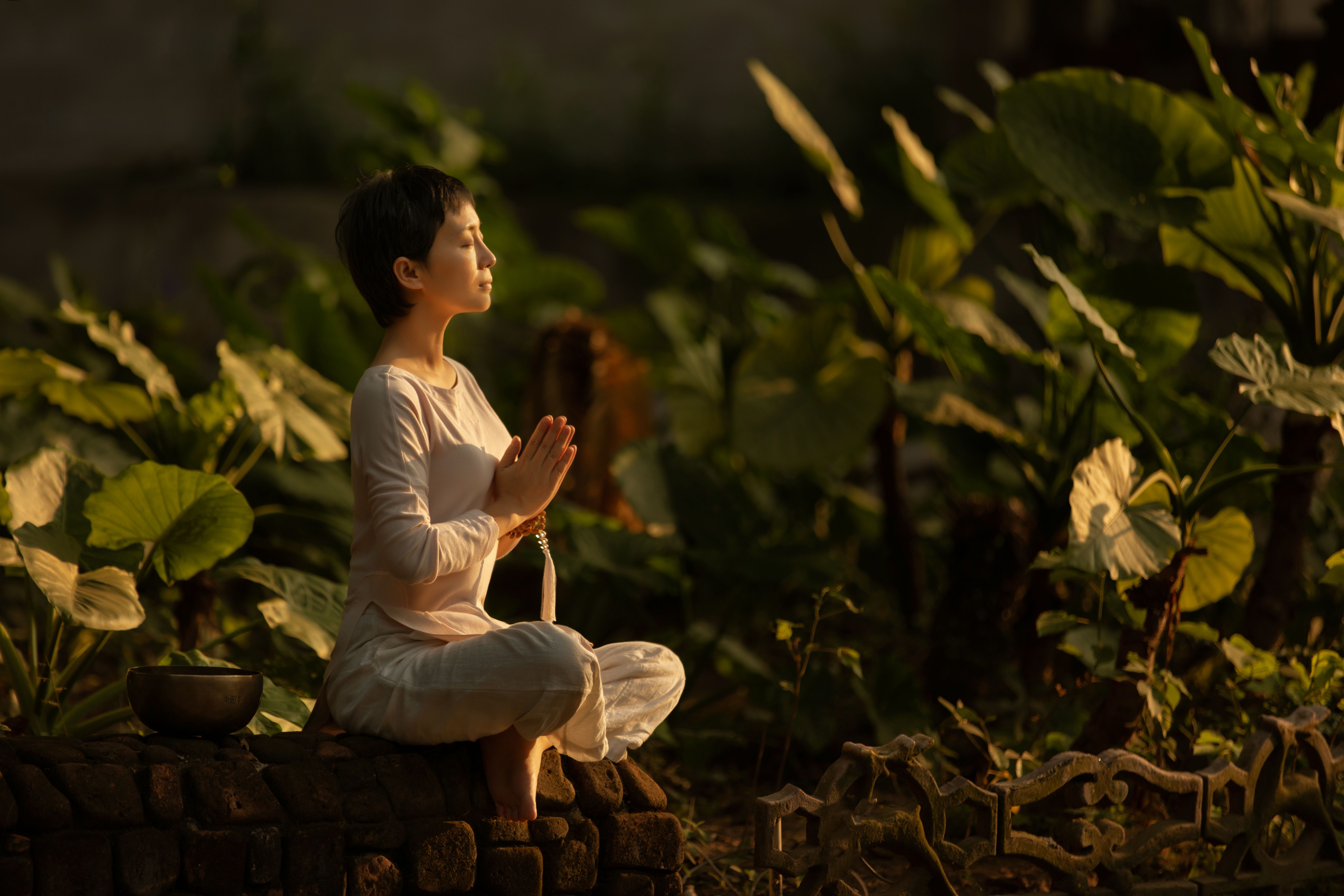 Woman meditating peacefully in a lush garden in the morning light