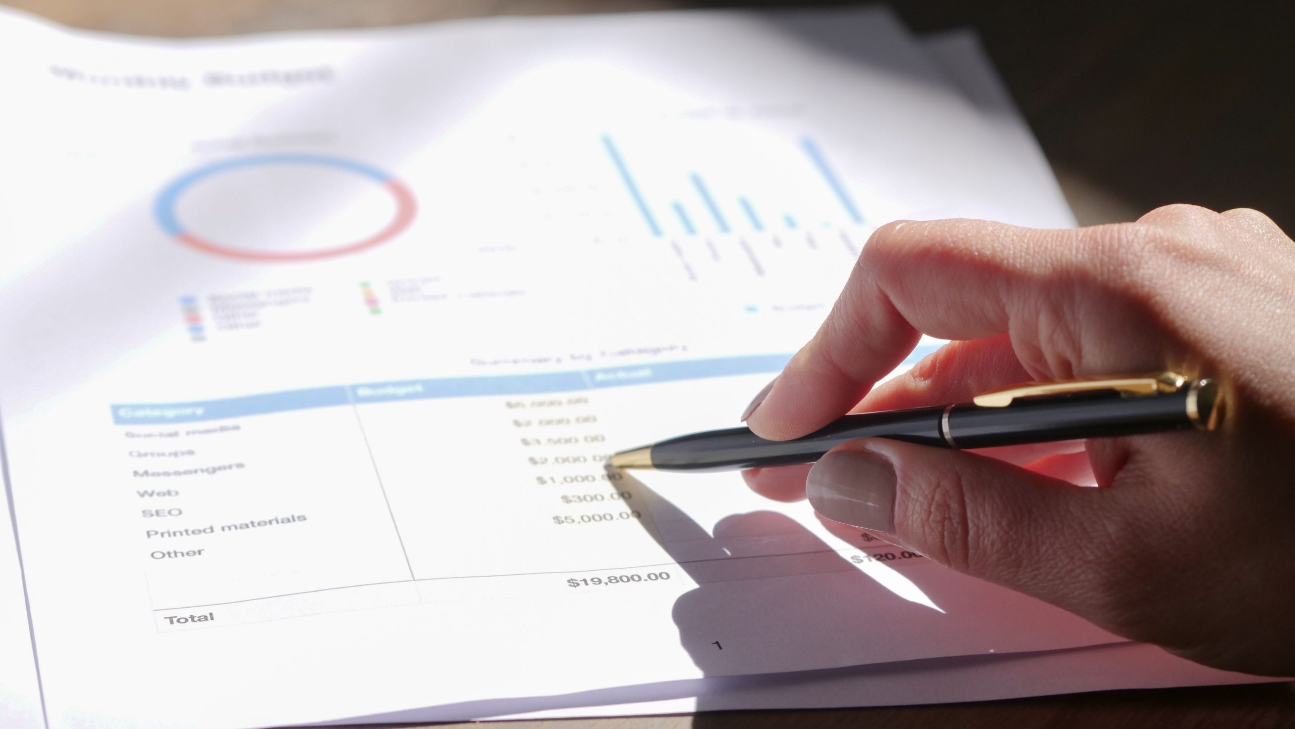 Person analyzing a budget with charts and graph paper, illustrating clear financial reporting.