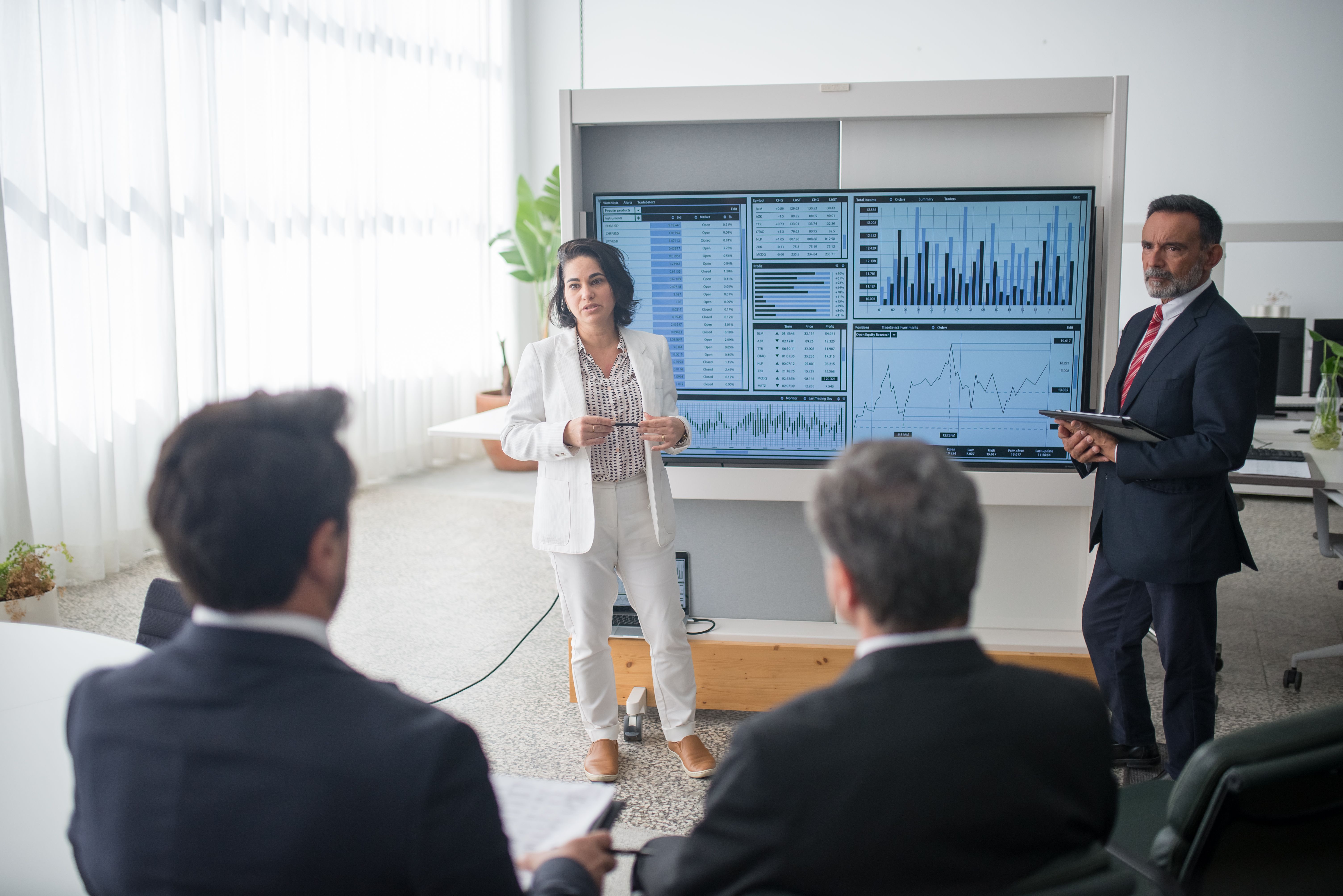 Colleagues discussing financial charts during a corporate meeting, illustrating accountability and shared understanding.