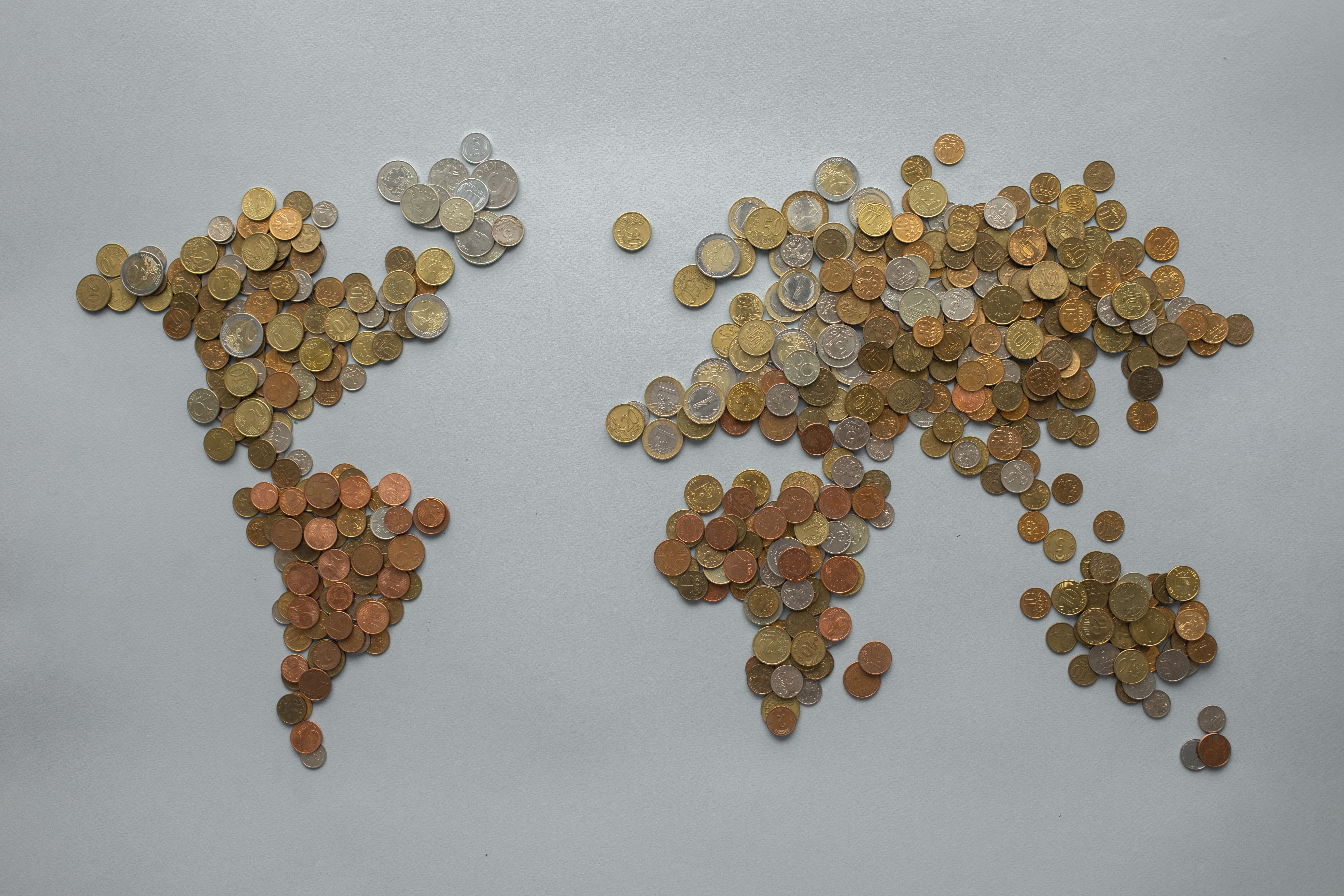 Creative world map made from assorted coins on a gray backdrop, symbolizing global finance.