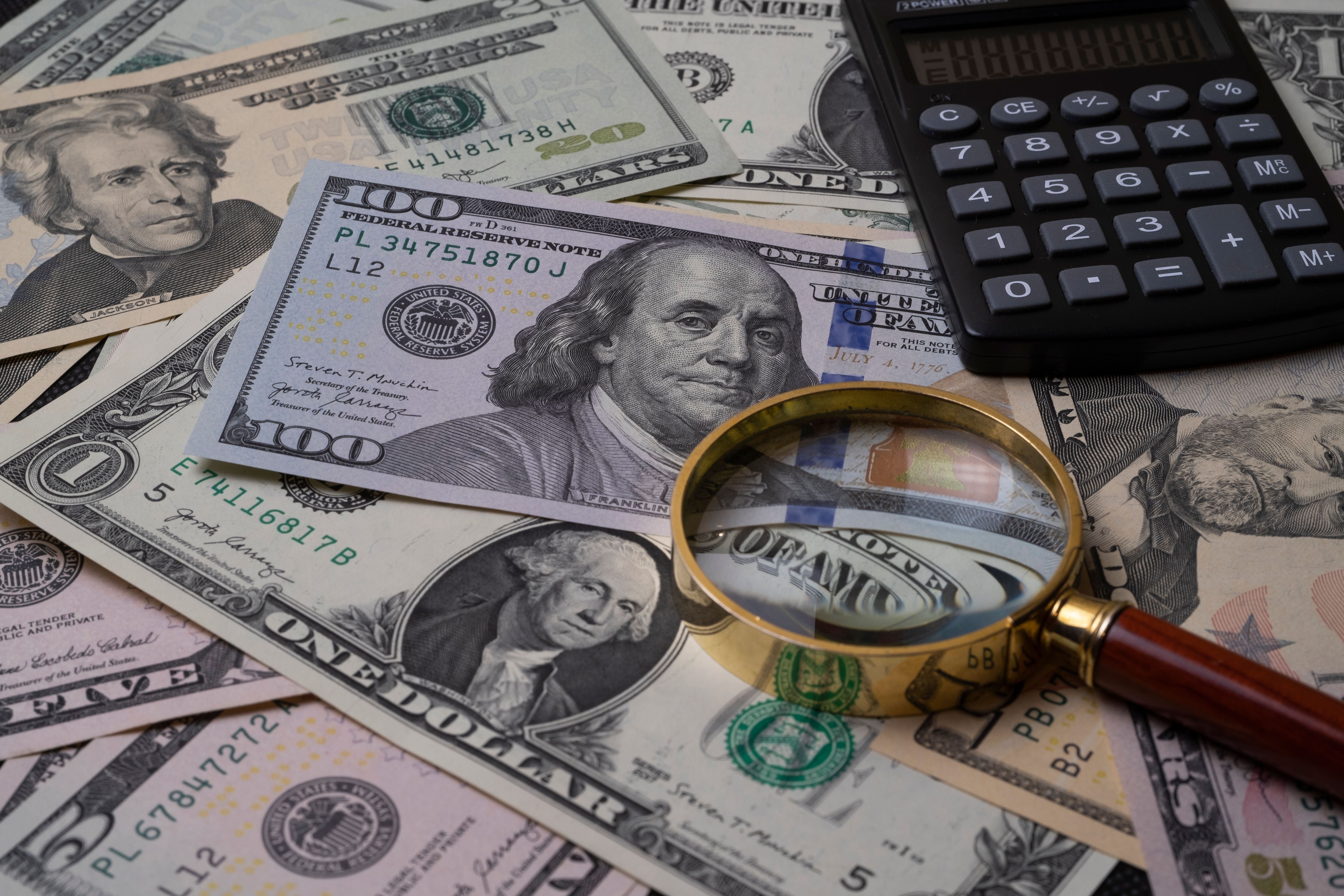 US currency with a magnifying glass and calculator illustrating financial transparency in litigation finance