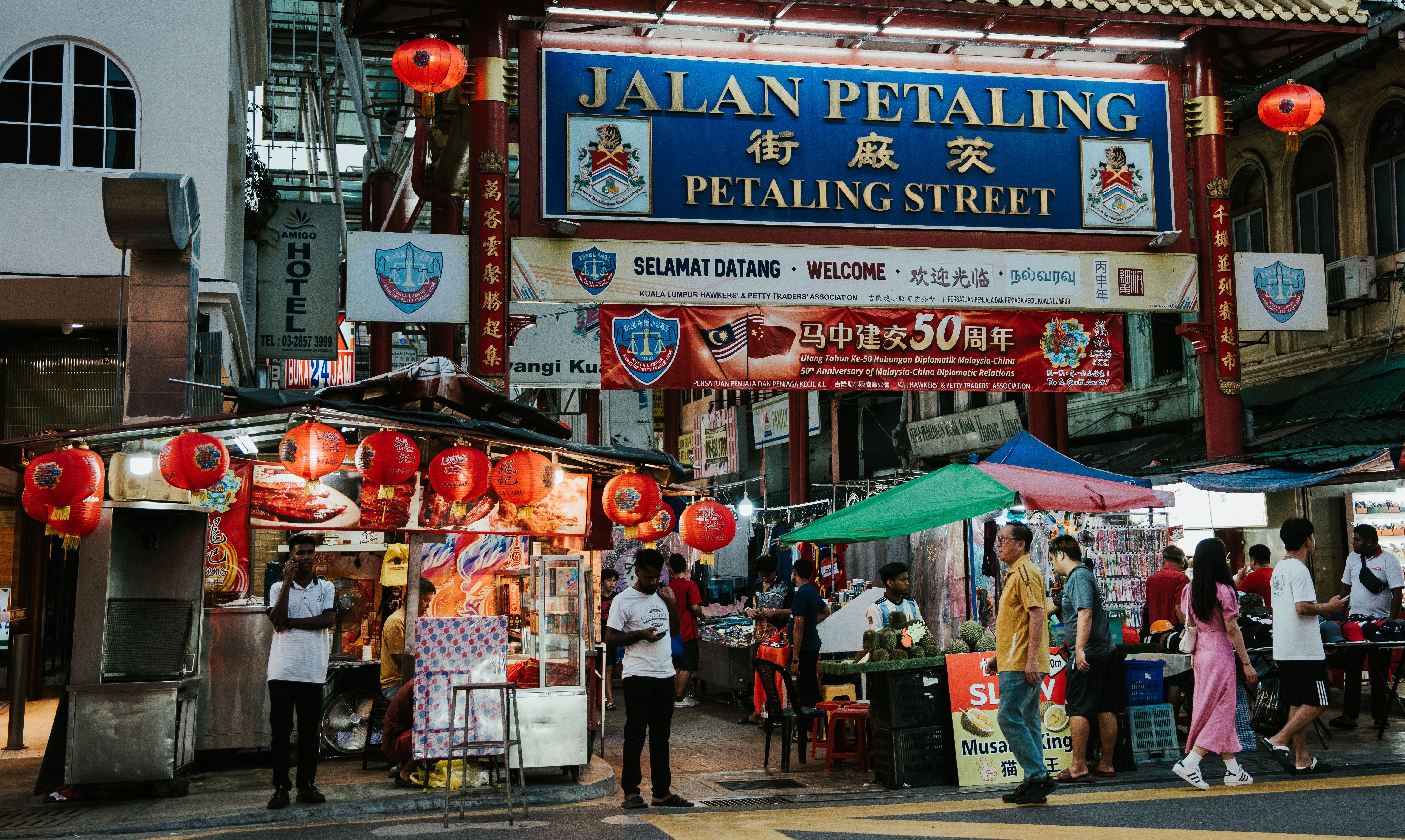 Busy Petaling Street market in Kuala Lumpur with vendors, stalls, and visitors.